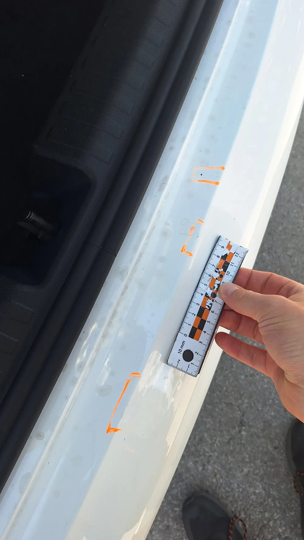 Zdjęcie SIXT: górna krawędź tylnego zderzaka przy bagażniku z drobnymi śladami obrysowanymi markerem